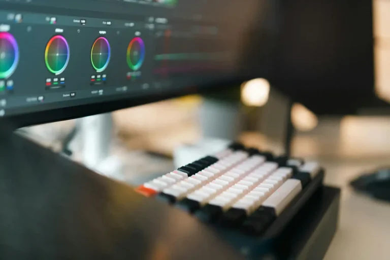 Professional video editing setup showing color grading tools on a monitor and mechanical keyboard for content creation